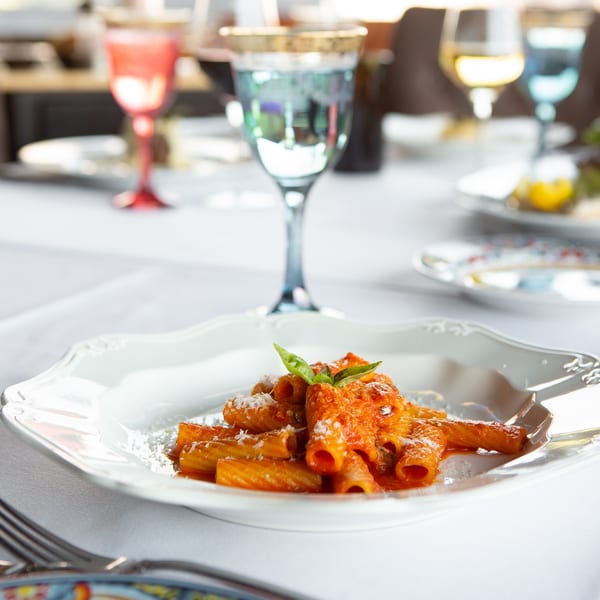 Rigatoni pasta with red sauce, parmesan, and basil on a white plate at Antica Sicilia.
