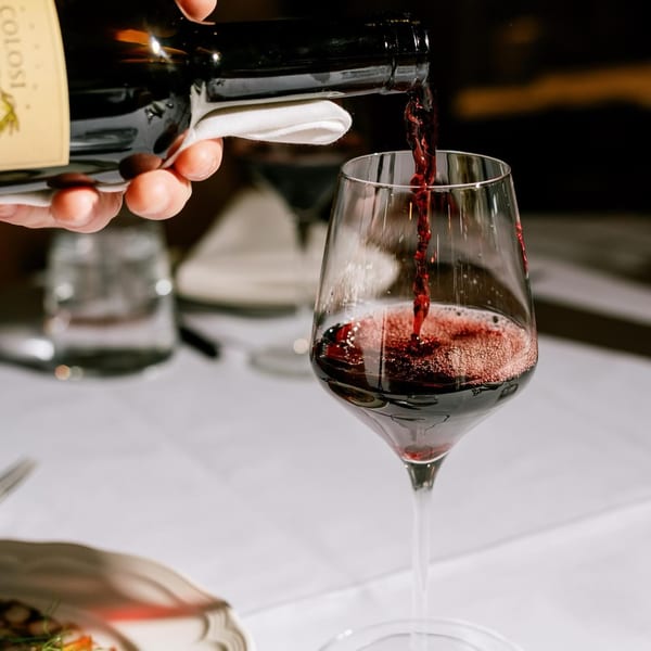 Red wine from a bottle being poured into a glass at Antica Sicilia.
