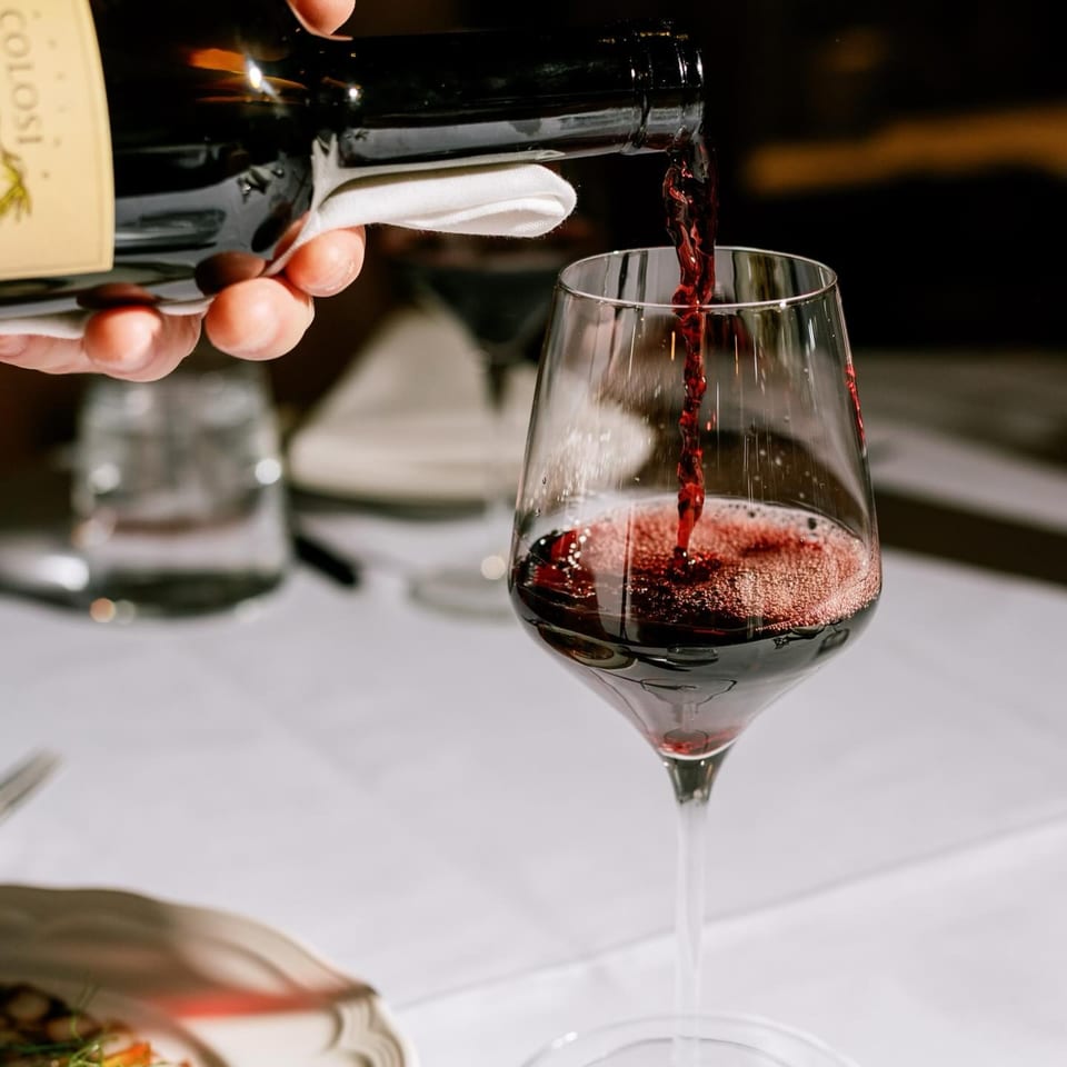 Red wine from a bottle being poured into a glass at Antica Sicilia.